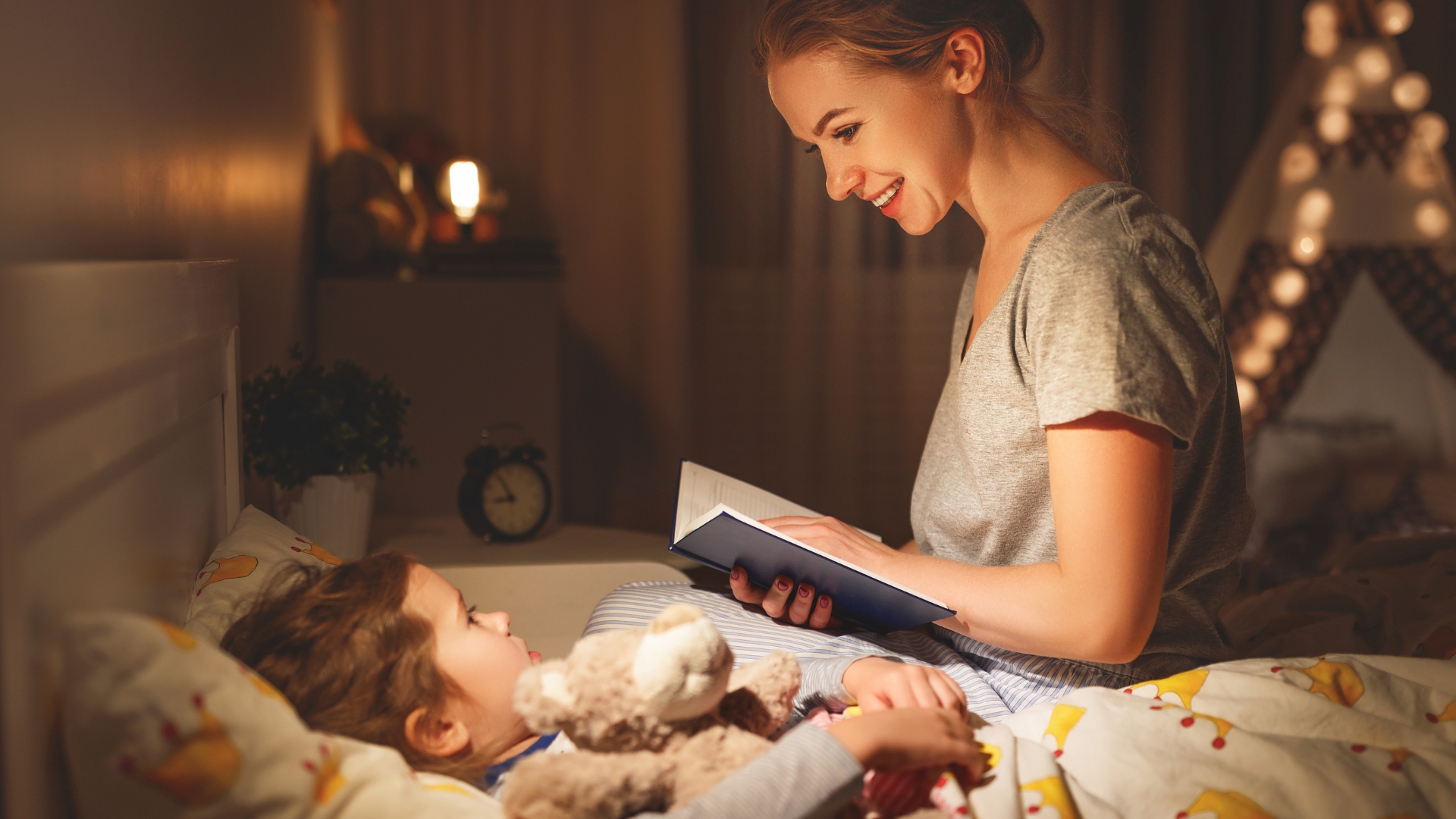 A mother reading a story to her child during bedtime via Canva.